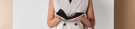 Shoe size guide. Woman holding black espadrille flats.